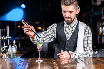 Expert tapster places the finishing touches on a drink while standing near the bar counter in bar