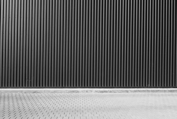 Wall of metal warehouse and pavement. Black and white