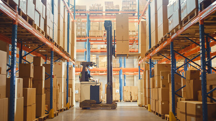 Retail Warehouse full of Shelves with Goods: Electric Forklift Truck Operator Lifted Pallet with Cardboard Box on a Shelf. Working in Logistics Storehouse Product Logistics and Delivery Center