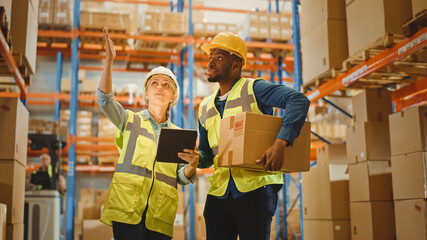 Retail Warehouse full of Shelves with Goods in Cardboard Boxes, Male and Female Supervisors Use Digital Tablet and Look For a Right Shelf. Forklift Working in Logistics Storehouse