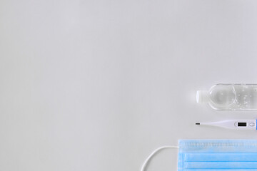 white thermometer lies on a light background antiseptic and a blue mask