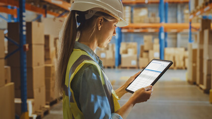 Professional Female Worker Wearing Hard Hat Uses Digital Tablet Computer with Inventory Checking...