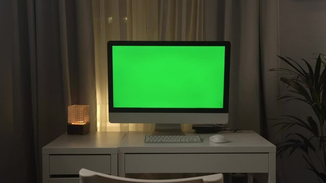 Green screen laptop computer sitting on a home work desk next to a desk lamp. Footage shot with RED, available in 4K and HD. Download the preview for free.