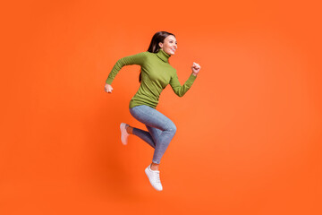 Fototapeta na wymiar Full body profile side photo of young attractive crazy girl happy smile run jump up look empty space isolated over orange color background