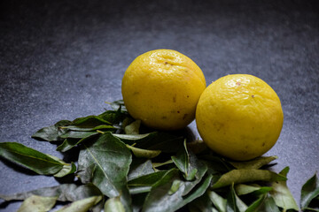 Picture of fresh ripe two yellow lemon with some curry leaves