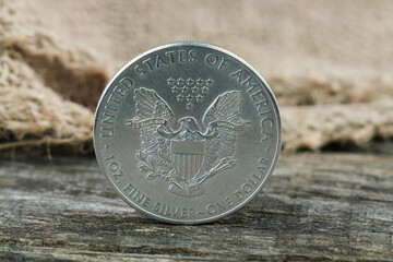 Eine Unze Feinsilber / Silbermünze (1 Oz American Silver Eagle) steht auf einem rustikalen...