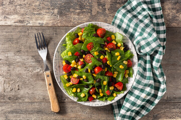 Mexican salad with black beans, corn,tomatoes,lettuce and pepper on wooden table
