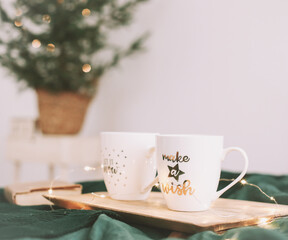 Cozy bedroom with coffee mugs and book in bed. Christmas still life. Breakfast in bed. Flat lay. Holidays, Christmas concept