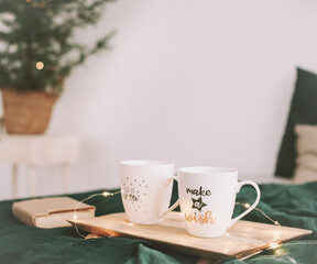 Cozy bedroom with coffee mugs and book in bed. Christmas still life. Breakfast in bed. Flat lay. Holidays, Christmas concept