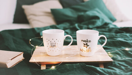 Cozy bedroom with coffee mugs and book in bed. Christmas still life. Breakfast in bed. Flat lay. Holidays, Christmas concept