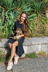 Portrait of a beautiful young girl with a cat in her arms on a park background.