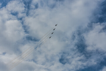 four fighter planes fly up steeply at a blue sky