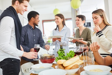 Freunde vor gemeinsamer Mahlzeit in einer WG Küche an gedecktem Tisch