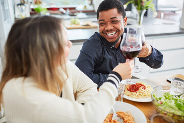 Freunde stoßen am Tisch mit Rotwein an beim Pasta Essen