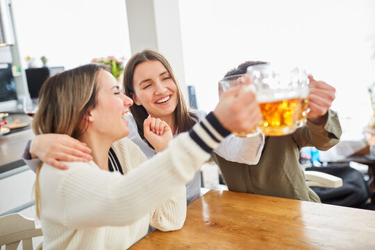Glückliche Frauen umarmen sich beim Fußball schauen und stoßen mit Bier an