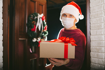 courier delivers a gift on Christmas Eve in a mask from the coronavirus