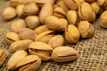 Salted pistachios lie on the burlap. Close up.