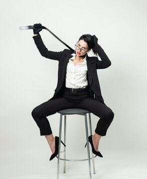 a woman in black office clothes and gloves is sitting on a chair with a belt around her neck