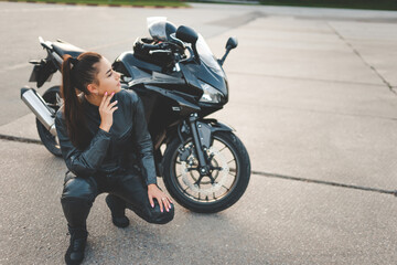 Biker girl in a leather suit near her motorcycle