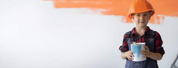 a boy dressed in overalls stands in the room holding a can of paint in his hands. Home renovation...