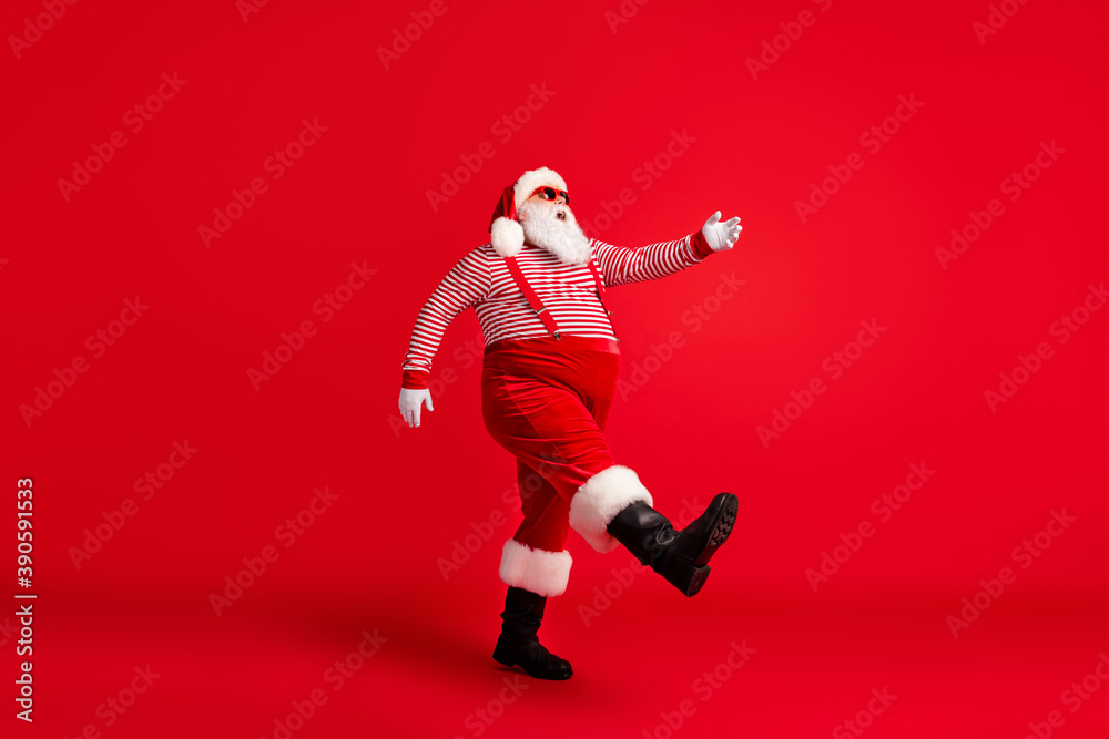 Sticker Full length profile photo of grandfather grey beard step raise hand wear santa claus x-mas costume suspenders sunglass striped shirt cap boots isolated red color background