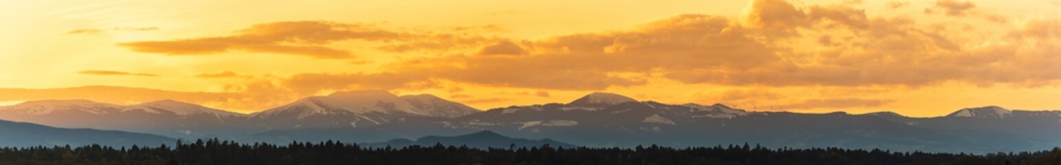 Styrian Lavanttaler Alps covered with snow in orange light of sunset. Background or banner