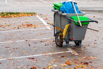 Symbolbild: Strassenreinigung, Umweltverschmutzung: Wagen mit Müllbeuteln, Besen und Reinigungszubehör auf einem Parkplatz im Herbst