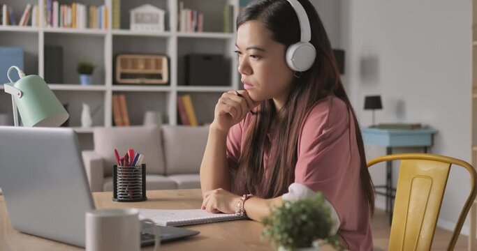 asian chinese student online class lesson distance education,young woman with headset does homework at home watching a video lecture at the computer laptop