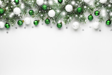 Christmas snow border of shiny white and green balls, evergreen branches on a white wooden background. New year card