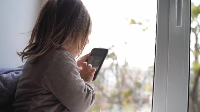 toddler child using phone at home, taking photos and playing games