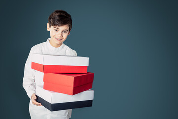 Obraz premium handsome teen boy with red and white colored present boxes holding that tower in his hands and smile in camera beeing happy for christmas holidays