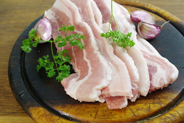 raw bacon with parsley on white plate