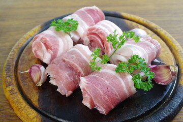 raw bacon with parsley on white plate