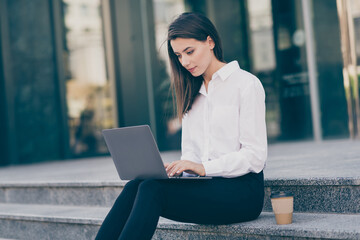Photo of serious sweet young woman assistant wear white formal shirt typing modern device sitting stairs outdoors