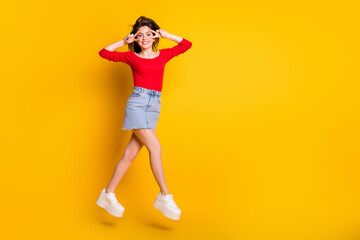 Fototapeta na wymiar Full length body size view of her she nice attractive pretty cheerful cheery skinny girl jumping having fun showing v-sign isolated over bright vivid shine vibrant yellow color background