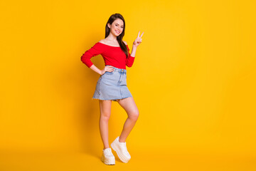 Fototapeta na wymiar Full size photo of attractive pretty girl enjoy weekend holiday make v-sign wear denim red tank top gumshoes isolated over bright shine color background