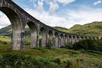 Fototapeta na wymiar The Scottish landscape with famous Glenfinnan Viaduct in Scotland from bottom with blue sky and clouds