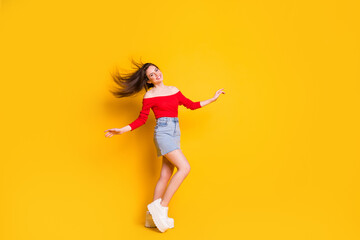 Fototapeta na wymiar Full body size photo of charming pretty young girl aired hair dance party celebrating wear shirt open shoulders denim mini skirt sneakers isolated bright yellow color background