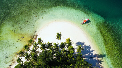 Small Island with beautiful beach, palm trees by turquoise water view from above. Britania Islands, Surigao del Sur, Philippines.