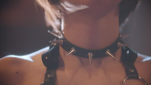 Sexy woman puts on a black studded collar