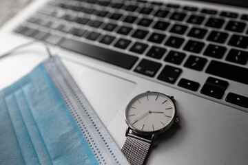 Maseczka i zegarek leżąca na klawiaturze laptopa - obrazy, fototapety, plakaty