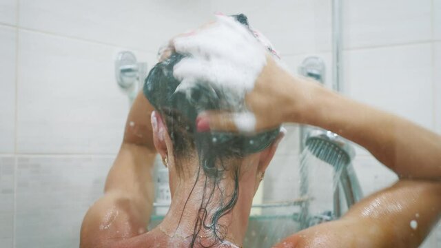 Woman in the shower showering under refreshing water.