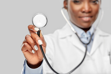 medicine, profession and healthcare concept - close up of happy smiling african american female doctor in white coat with stethoscope over background