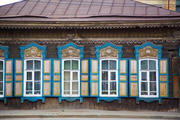 Wall of an old wooden house with carved windows with shutters. Horizontally.