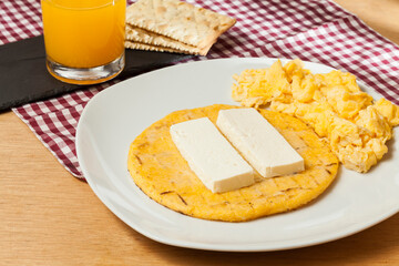 Tasty traditional breakfast in Colombia; Arepa of yellow corn with cheese and scrambled eggs.