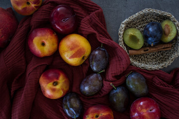 Flat lay photo of fresh fruits. Juicy nectarines, plums, cinnamon, rosemary and kitchen knife on a table. Vibrant colors of garden fruits. 