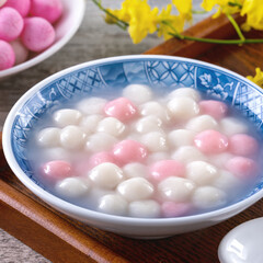 Close up of red and white tangyuan in blue bowl on wooden background for Winter solstice.