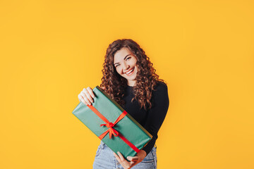 Woman holding large box in her hands. Gift in green packaging with red ribbon and red bow. Gift for woman for holiday or special occasion
