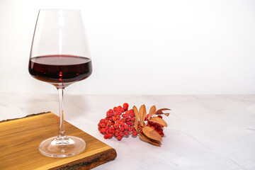 a glass of red wine on a Board with Rowan berries