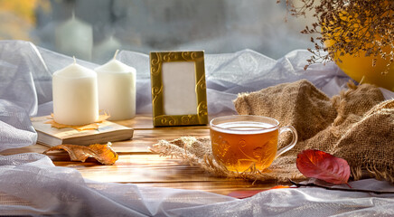 Autumn tea composition with a Cup of tea, photo frame and candles. Home comfort. Family. Selective focus.